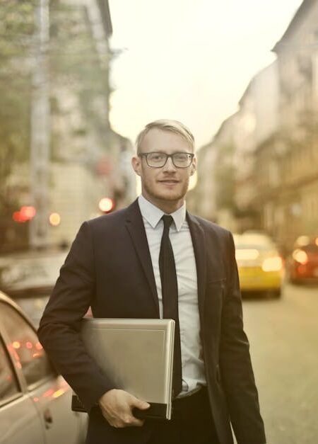 Businessman in a suit holding a laptop on a busy city street. Urban professional life.